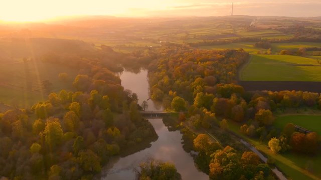Aerial footage during late Fall Autumn of a river reflecting the sunset over rural England in the countryside, West Yorkshire, UK - Wakefield