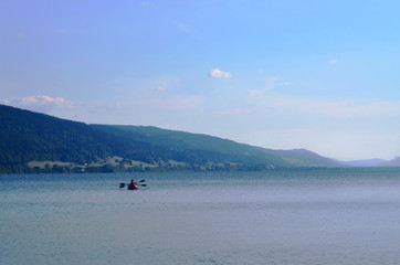 People floating in an inflatable red boat and paddling. Mountain lake Zhu in Switzerland.