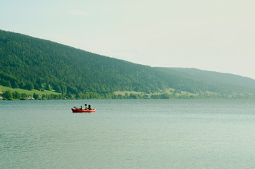 People floating in an inflatable red boat and paddling. Mountain lake Zhu in Switzerland.
