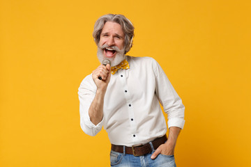 Cheerful elderly gray-haired mustache bearded man in shirt bow tie isolated on yellow background....