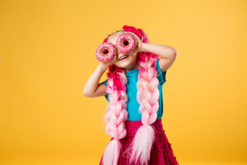 little girl with donuts on yellow background isolate, space for text