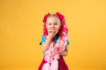 little girl with donuts on yellow background isolate, space for text