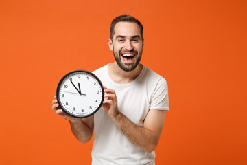Cheerful young man in casual white t-shirt posing isolated on bright orange wall background studio...