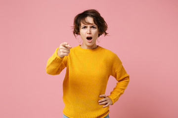 Shocked angry young brunette woman girl in yellow sweater posing isolated on pastel pink background, studio portrait. People lifestyle concept. Mock up copy space. Pointing index finger on camera.