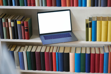 Computer between colorful books