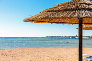 Beach with straw umbrellas and sunbeds. Egyptian resort in Sharm el Sheikh. Vacation concept.