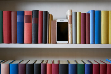 Mobile phone in bookshelf with sorted books