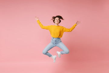 Fototapeta na wymiar Smiling young brunette woman girl in yellow sweater posing isolated on pastel pink background. People lifestyle concept. Mock up copy space. Jumping, hold hands in yoga gesture, relaxing meditating.