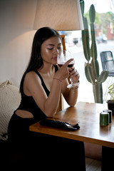 Asian girl in a cafe. Beautiful Balinese women with glass of wine with window reflection