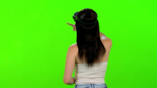 Drawing happily in a VR game or app by a young woman over green screen, using remotes, casual look.
