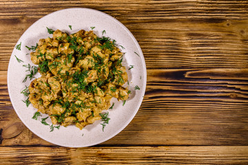 Plate with champignons stewed in sour cream on a wooden table. Top view