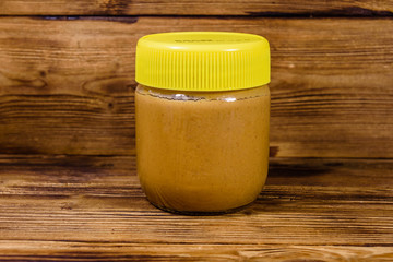 Glass jar with peanut butter on a wooden table