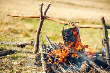 travel photography life style concept of camp fire tongues of flame and camping cauldron cooking breakfast in hiking time in mountains 