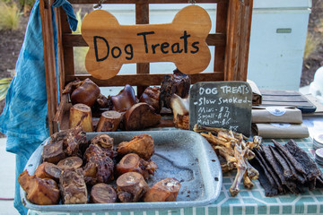 An assortment of natural dog treats made of smoked beef, pork and chicken parts, for sale at an outdoor market.