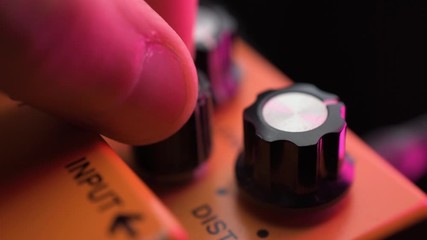 adjusting tone distortion knobs on a electric guitar effect pedal - Powered by Adobe