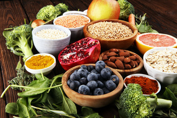 Healthy food clean eating selection: fruit, vegetable, seeds, superfood, cereals, leaf vegetable on rustic background