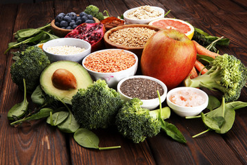 Healthy food clean eating selection: fruit, vegetable, seeds, superfood, cereals, leaf vegetable on rustic background
