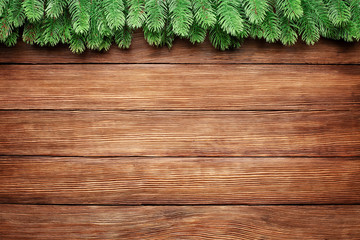 green branches of a fir tree on wooden planks background, christmas frame with copy space