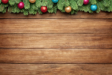 green branches of a fir tree with christmas balls on wooden planks background, christmas frame with...