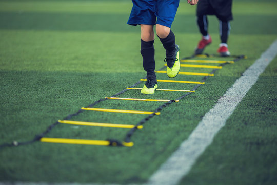 Kid soccer player Jogging and jump between ladder drills for football training. Ladder drills exercises for football or soccer team. Kid soccer player exercises on ladder drills.