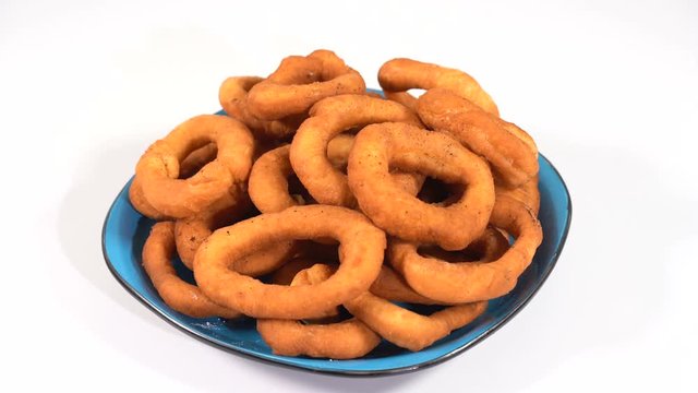A lot of fresh fried doughnuts in a plate on the table spinning in front of the camera
