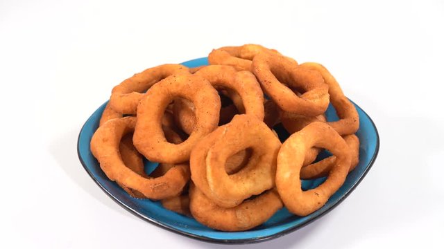 A lot of fresh fried doughnuts in a plate on the table spinning in front of the camera