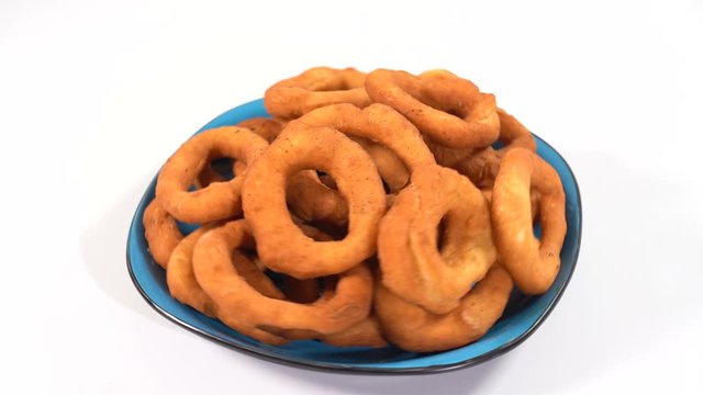 A lot of fresh fried doughnuts in a plate on the table spinning in front of the camera