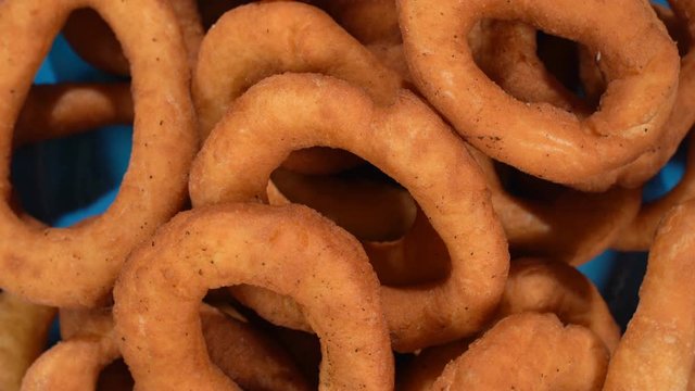A lot of fresh fried doughnuts in a plate on the table spinning in front of the camera. Close-up