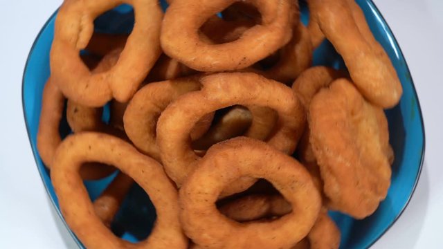 A lot of fresh fried doughnuts in a plate on the table spinning in front of the camera. Close-up