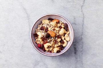 Bowl of granola with nuts, raisins, cranberries and chia seeds. Concept for a tasty and healthy meal. Stone background. Top view. Copy space.