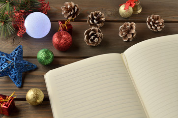 Christmas decorations, star and balls on wooden table. Notebook for new year greetings. Festive decoration, on a brown wooden table with space for text.