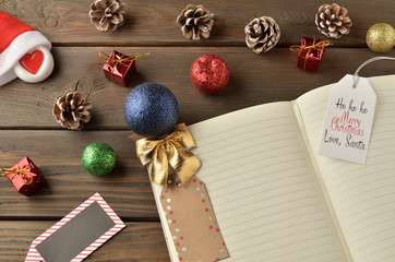 Christmas decorations, star and balls on wooden table. Notebook for new year greetings. Festive decoration, on a brown wooden table with space for text.