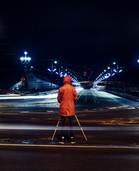 Unknown photographer in orange jacket taking photos of city