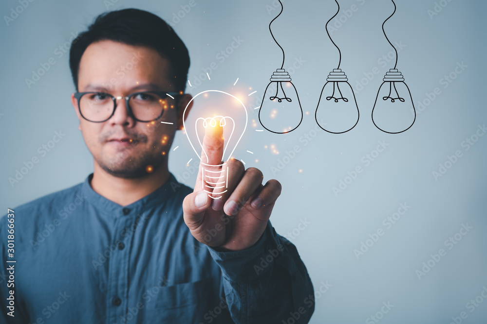 Leinwandbilder man touching on with idea light bulb front on gray wall background.creative idea.Concept of idea and innovation
