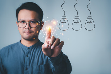 man touching on with idea light bulb front on gray wall background.creative idea.Concept of idea...