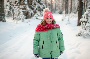 Fototapeta na wymiar Portrait of plump funny girl in winter clothes posing for camera in snowy forest.