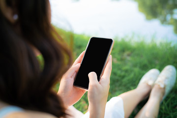 Beautiful women sitting on green grass use smartphone