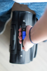 Man weighting luggage with digital scale