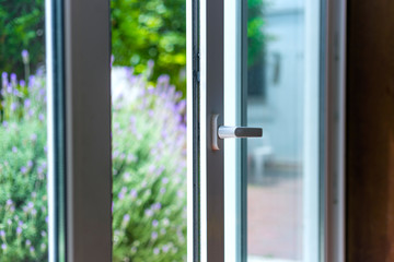 Opened door of a family home. Lock of the sliding door with the yard of background. White PVC door...