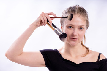 portrait of a beautiful young cute girl with makeup brushes on a white background