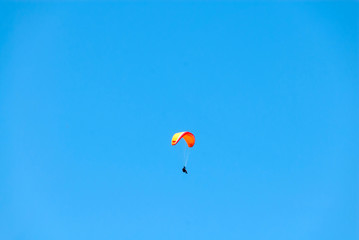 Fototapeta na wymiar Orange Hang Glider Soaring Through the Air