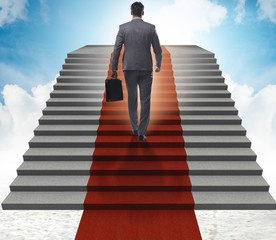 The young businessman climbing stairs and red carpet into sky