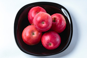 Red apples on a white plate, on a wooden, in a plate