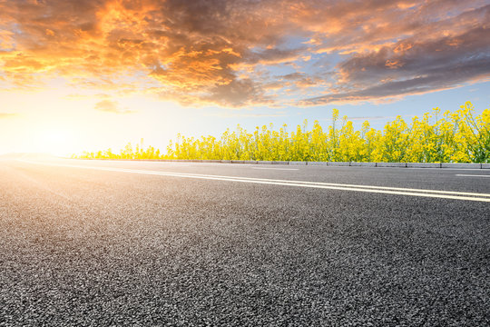 Empty Asphalt Road And Blooming Rape Flowers In Farmland Field.