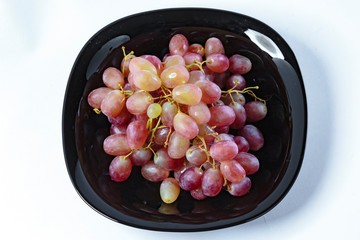 Grapes, on a white plate, on a wooden board, on a black plate