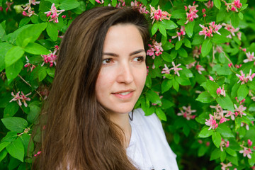 Young beautiful girl near the flowers. photon green and flowers. Portrait of young beautiful girl near flowers. Portrait of young beautiful woman, pretty face close-up, big pink lips, straight hair dr