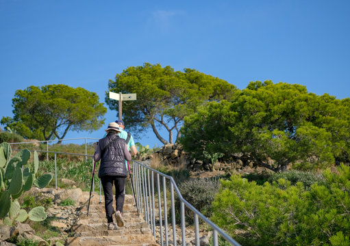 Elderly, senior couple with walking sticks travelling together in the hiking route of Catalonia. Couple hikers climbs a mountain path. Healthy, active lifestyle at any age. Walking trails, hiking.