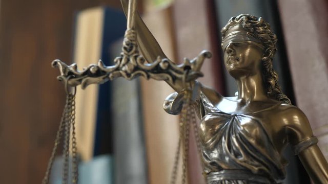 Statue of themis or lady justice. Femida on books background. Lawyer, law library concept