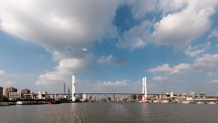 Shanghai Nanpu-brug bekeken in het midden van de Huangpu-rivier met witte wolken en blauwe hemelachtergrond, de vier Chinese karakters op de brug betekenen Nanpu-brug.