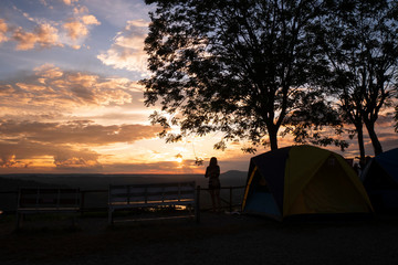 Silhouette people stand to watch the beautiful sunset at camping tent